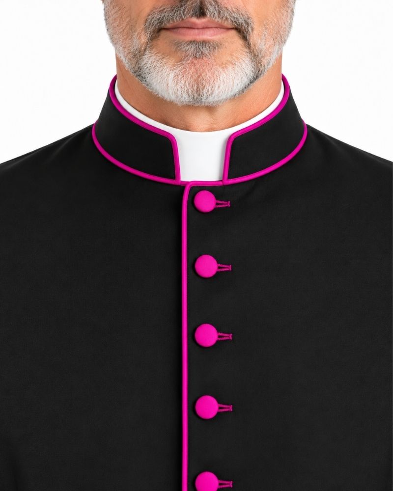 A closeup of a neck man wearing a Ambrose Bishop Cassock Black With Magenta Trim on plain white background.