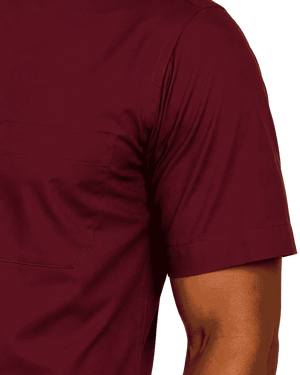 Close-up of a person wearing a short-sleeve clerical shirt in deep burgundy, showing the chest pocket and sleeve cuff against a plain white background.
