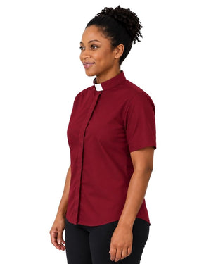 A woman wearing a short-sleeve burgundy clerical shirt with a contrasting white tab collar, paired with black trousers and a black belt, shown in a side-profile view against a plain white background.