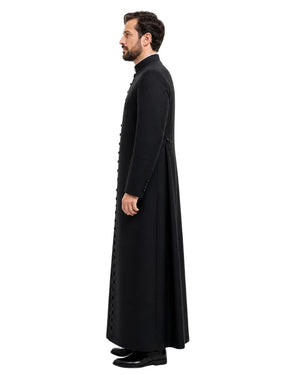 A man shown in profile wearing a long black cassock with a high collar and decorative button details, standing against a plain white background.