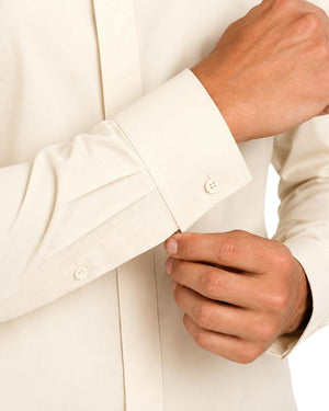 Close-up of a man's hands adjusting the cuff of an off-white long-sleeve clerical shirt.