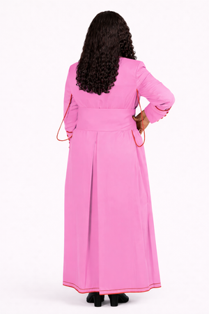 Person wearing a pink dress with long sleeves on a white background