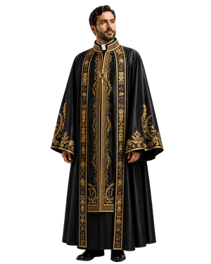 A man modeling a long black liturgical robe with ornate gold embroidery, a white collar, and a gold cross pendant, photographed against a plain white background.