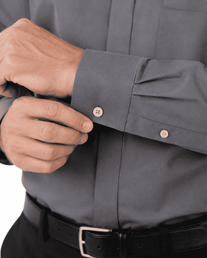 Close-up of a man's hands adjusting the cuff of a gray clerical shirt, with a black belt visible at the bottom.