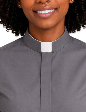 Close-up of a woman wearing a gray clerical shirt with a white collar roman, shown against a plain white background.