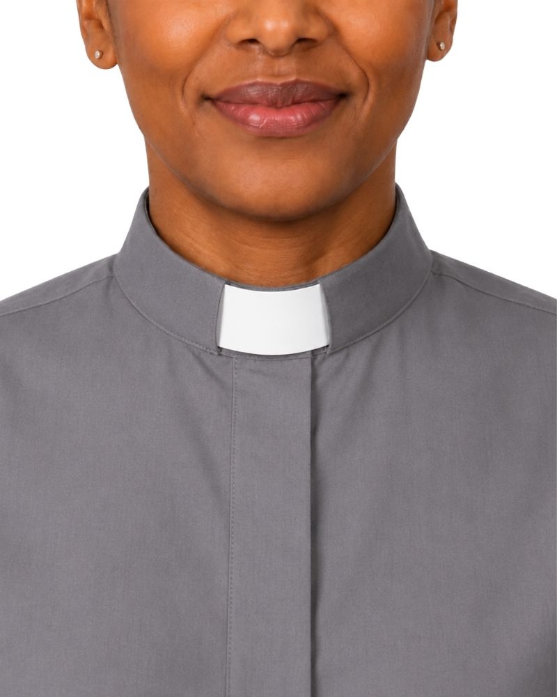 Close-up of a woman wearing a gray clerical shirt with a white clerical collar, shown against a plain white background.