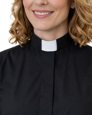A close-up of a woman wearing a black clerical shirt with a white collar, shown from the chest up against a plain white background.