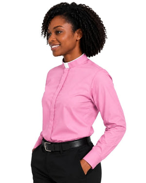 A woman wearing a pink long-sleeve clerical shirt with a white collar, paired with black trousers and a black belt, shown against a plain white background.