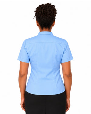 A woman viewed from the back wearing a light blue short-sleeve clerical shirt and black pants against a plain white background.