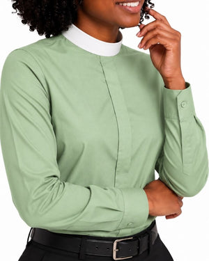 A woman wearing a sage green long-sleeve clerical shirt with a contrasting white mock neck collar, paired with a black belt.