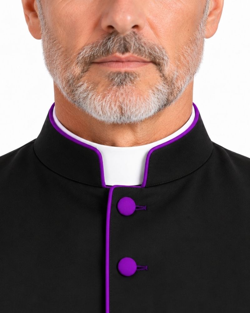 Close-up of a man wearing a Black Clergy Robe With Roman Purple Accents with a white collar and bright purple trim and buttons, against a plain white background.