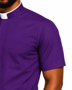 A close-up of a man wearing a purple short-sleeve clerical shirt with a white collar, showing the chest pocket and shoulder area against a plain white background.