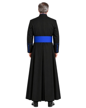 A man viewed from the back wearing a Black Clerical Cassock With Royal Blue Trim with a wide royal blue sash at the waist and blue button accents on the sleeves, against a plain white background.