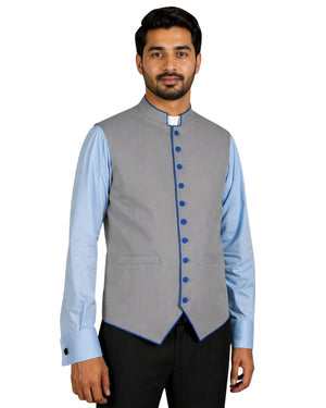 Man wearing a gray vest with blue buttons over a light blue shirt on a white background.