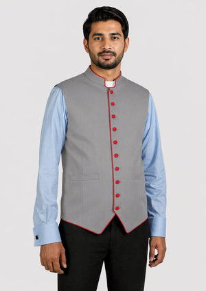 Man wearing a gray vest with red buttons over a light blue shirt on a white background