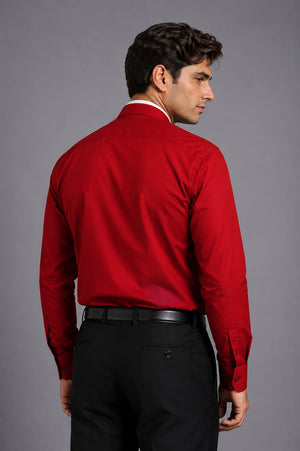 Man wearing a red dress shirt and black pants against a gray background