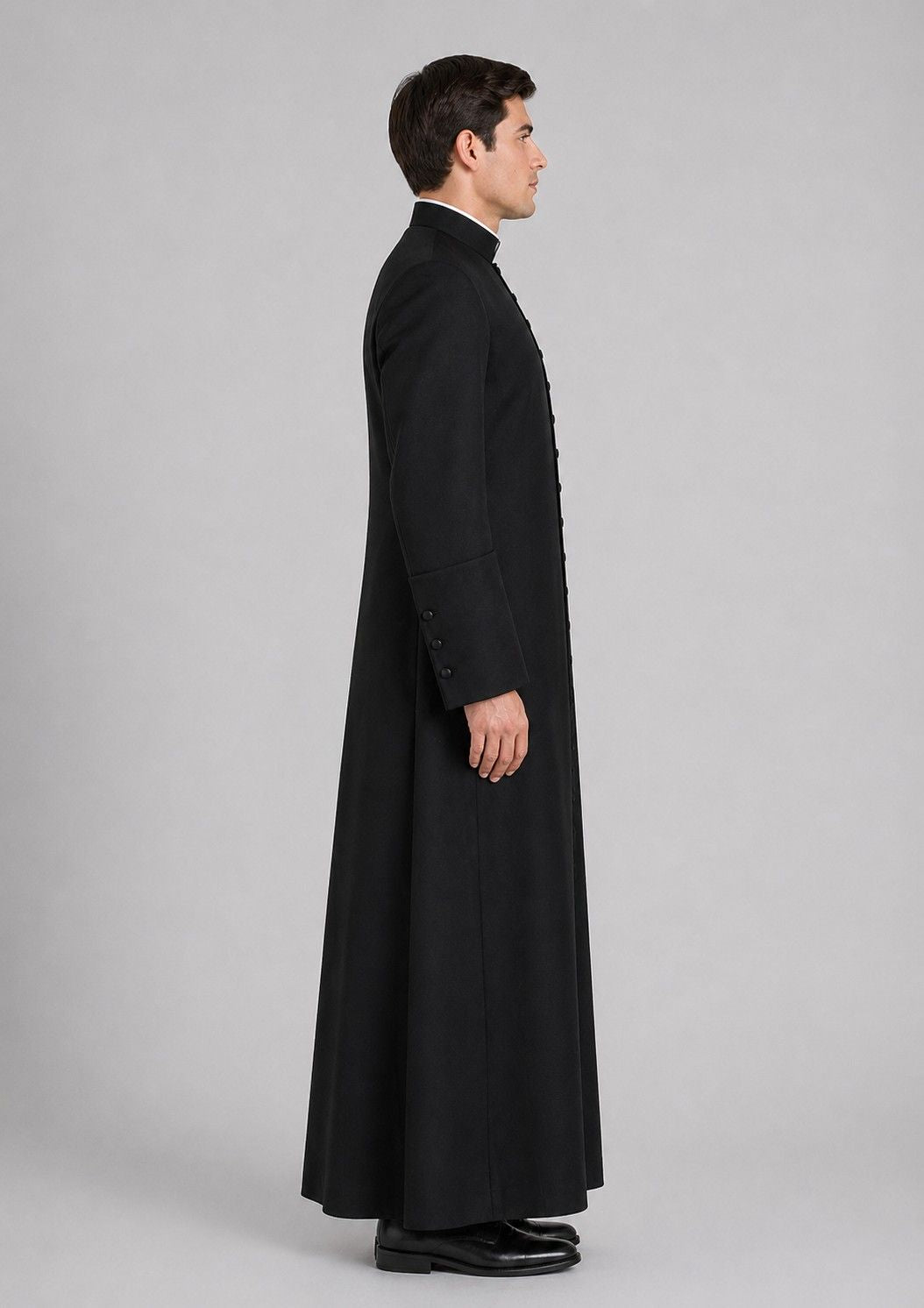 Man wearing a long black coat on a gray background