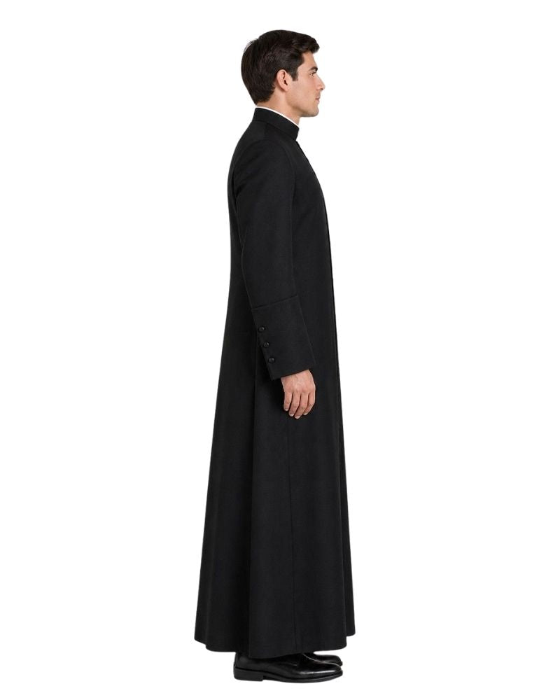 A man shown in profile wearing a long black clerical robe over a white shirt, photographed against a plain white studio background.
