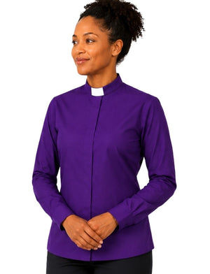 A woman wearing a purple long-sleeve clerical shirt with a white collar, standing against a plain white background.