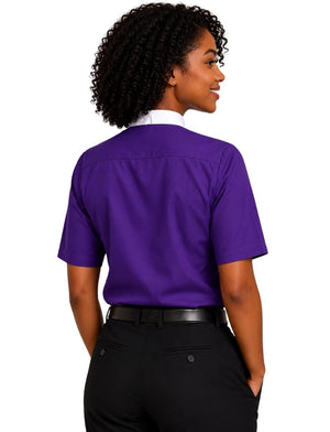 A woman shown from the back wearing a short-sleeve purple clerical shirt tucked into black trousers, against a plain white background.