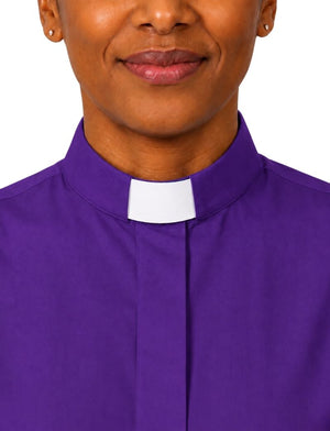 A close-up of a woman wearing a purple clerical shirt with a white collar tab, shown against a plain white background.