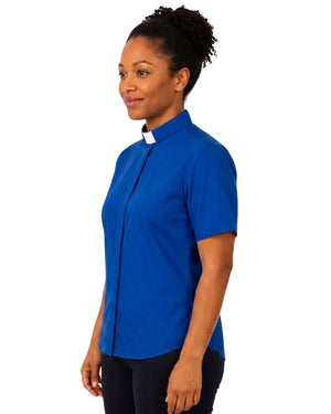 A woman wearing a royal blue short-sleeve clerical shirt with a white collar, standing against a plain white background.