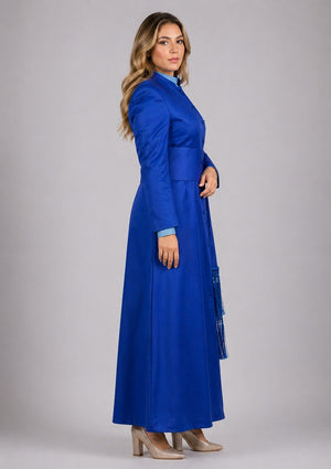 Woman wearing a long blue coat on a gray background