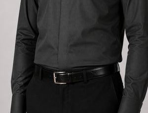 Person wearing a black shirt and pants with a black belt on a light gray background