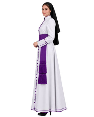 A woman modeling a White Clerical Cassock With Purple Trim, a purple waist sash, and a black veil, shown against a plain white background.