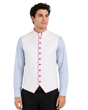 Man wearing a light blue clerical shirt white vest with pink buttons on a white background.