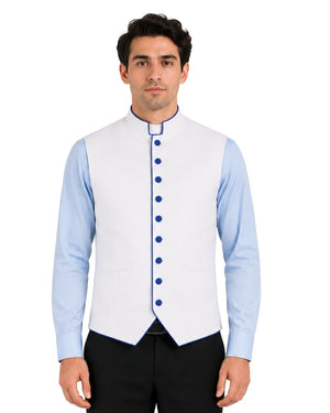 Man wearing a light blue clerical shirt white vest with blue buttons on a white background.