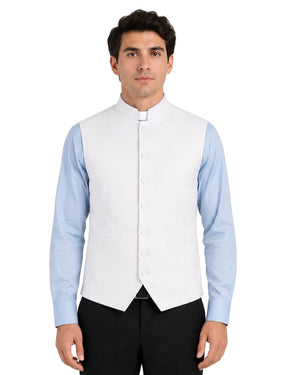 Man wearing a light blue clerical shirt white vest with white buttons on a white background.