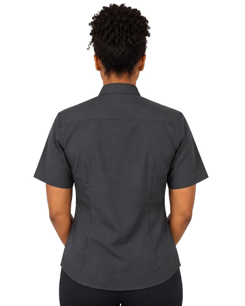 A woman viewed from the back wearing a dark charcoal gray short-sleeve clerical shirt and black pants, set against a plain white background.