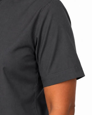 Close-up of a woman wearing a dark charcoal gray short-sleeve clerical shirt showing the sleeve cuff and side seam against a plain white background.