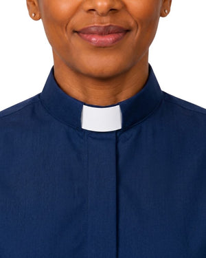 A close-up of a person wearing a navy blue collared shirt with a white clerical collar, shown from the chest up against a plain white background.