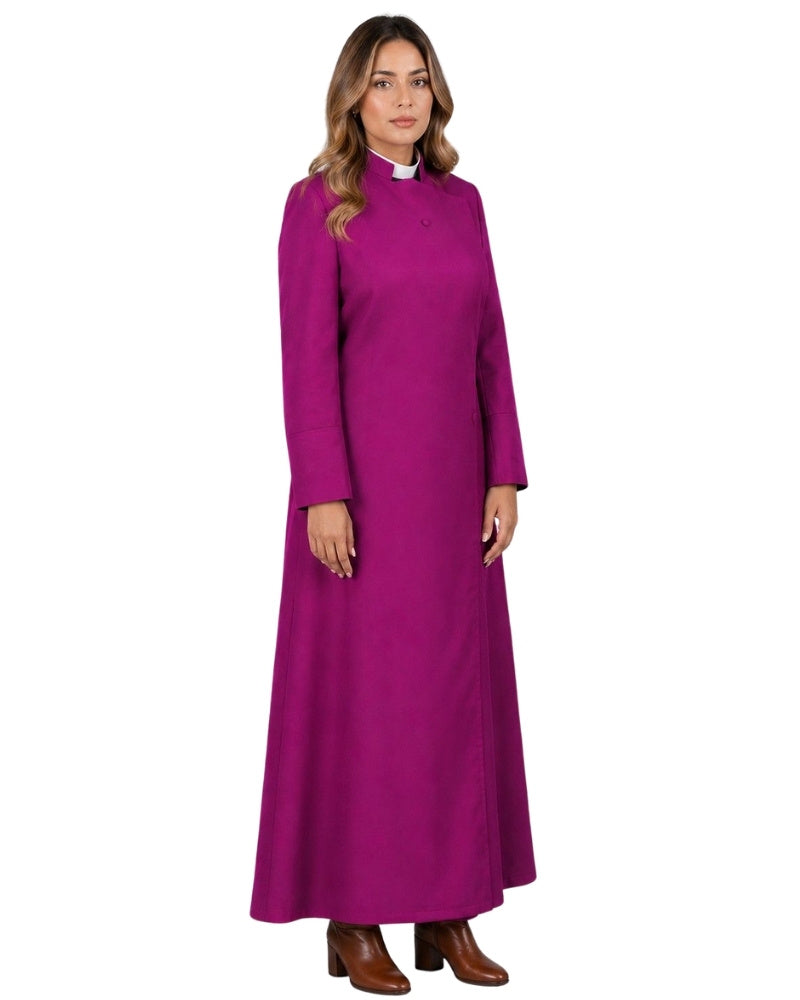 A woman wearing long magenta robe with a high mock neck, long sleeves, and a small button closure at the chest, paired with brown leather boots against a white background.