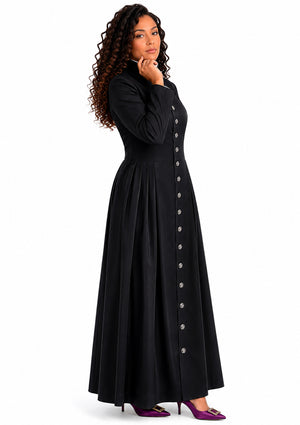 Woman wearing a long black robe with button details on a white background