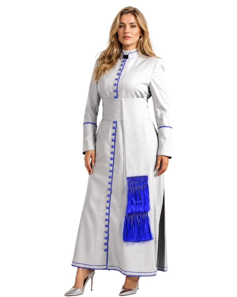 A woman modeling a long white or silver-gray traditional cassock with a bold royal blue sash and matching blue fringe, photographed against a plain white studio background.