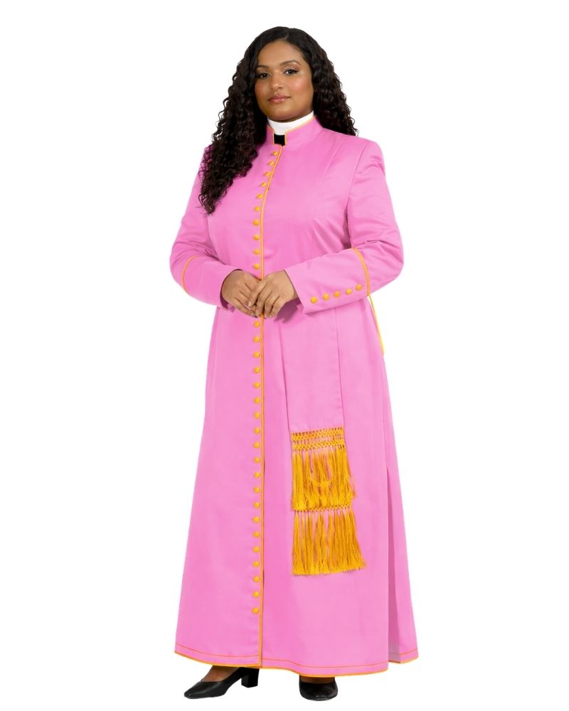 A woman modeling a bright pink cassock with gold trim, gold buttons, and a gold fringe detail on the front, paired with a white collar and black shoes, against a plain white background.