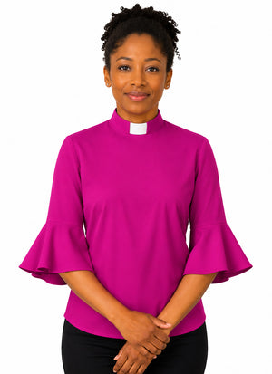 Woman wearing a bright pink clergy shirt with a white collar on a white background