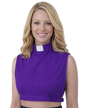 A smiling woman wearing a purple sleeveless mock-neck top with a white clerical collar, shown against a plain white background.