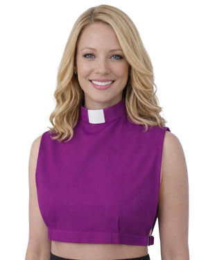 A smiling woman wearing a sleeveless purple mock-neck top with a white clerical collar, shown against a plain white background.