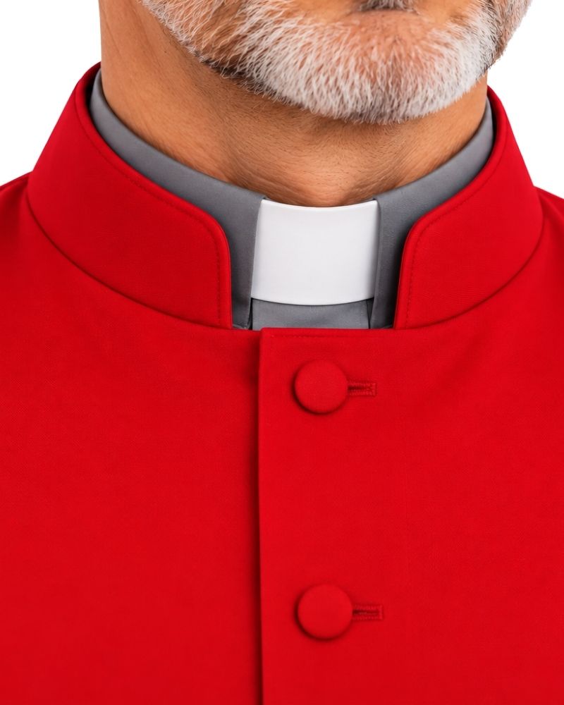 Close-up of a man wearing a Zaccai Red Sleeveless Clergy Robe with a white and gray clerical collar underneath, on a white background.