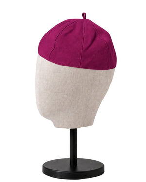 A clergy zucchetto cap displayed on a mannequin head stand. The top half of the cap is a deep magenta-purple, and the bottom half is a light beige heather fabric.