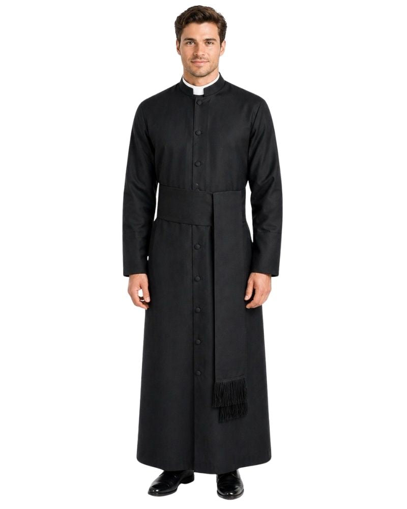 A man modeling a long black priestly robe with a collar, front buttons, a waist belt, and a black fringed drape, shown against a plain white background.