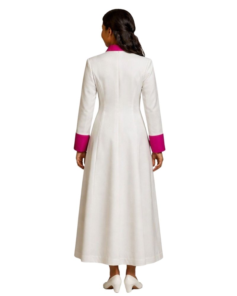 A woman viewed from the back wearing a long white cassock with bright pink contrast trim at the collar and cuffs, standing against a plain white background.
