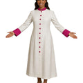 A woman modeling a long white cassock with a bright pink collar and cuffs, featuring a pink button-down front and white heels, set against a plain white background.