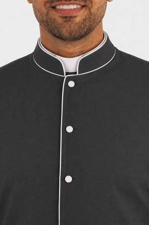 Black cassock with white buttons worn by a man on a plain background