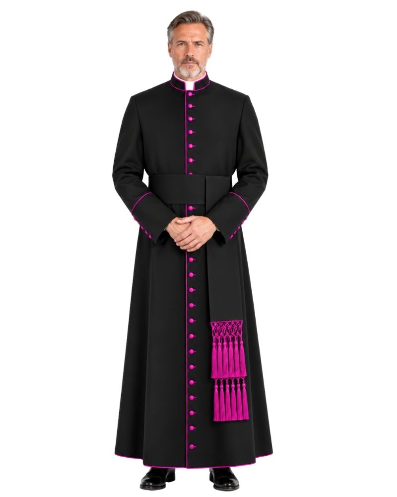 A man wearing a Ambrose Bishop Cassock Black With Magenta Trim magenta buttons, and a matching sash with tassels, photographed against a plain white background.