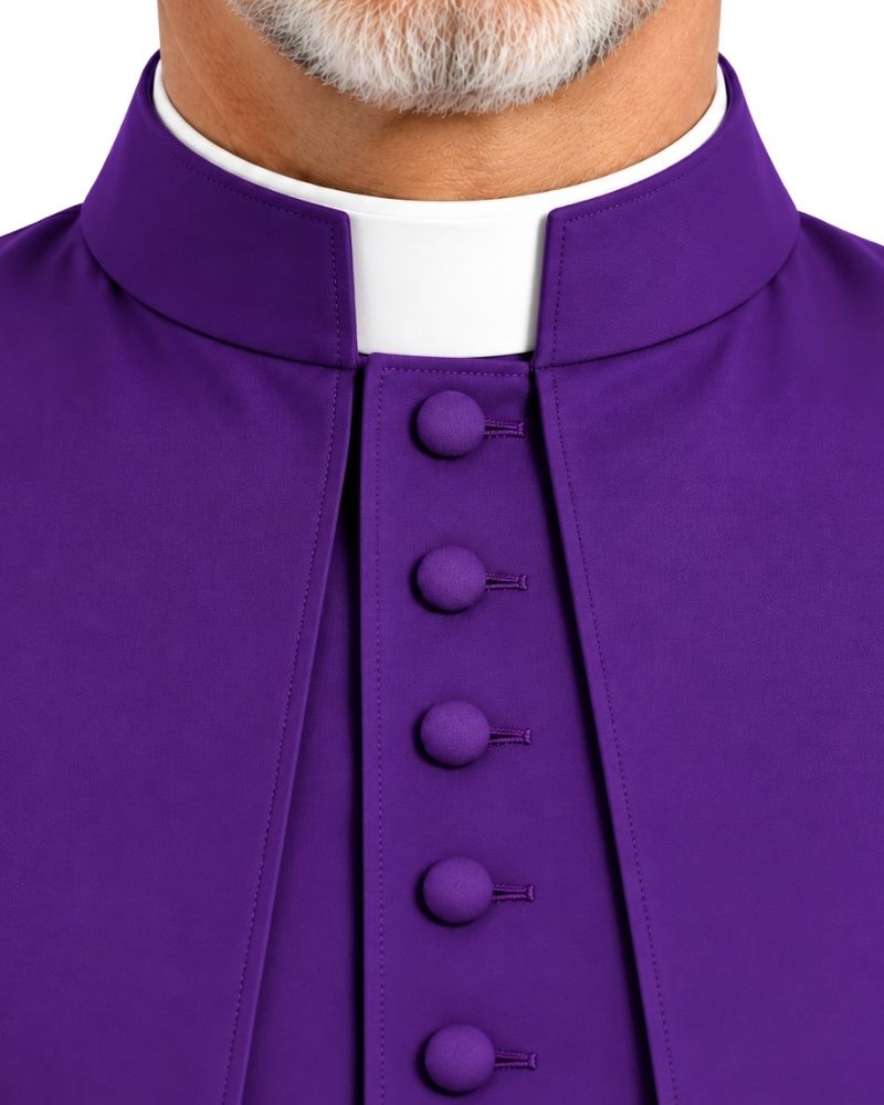 Close-up of a person wearing a Augustine Purple Cassock With Shoulder Cape with a white collar insert and purple buttons, cropped from the lower face to the chest against a plain white background.